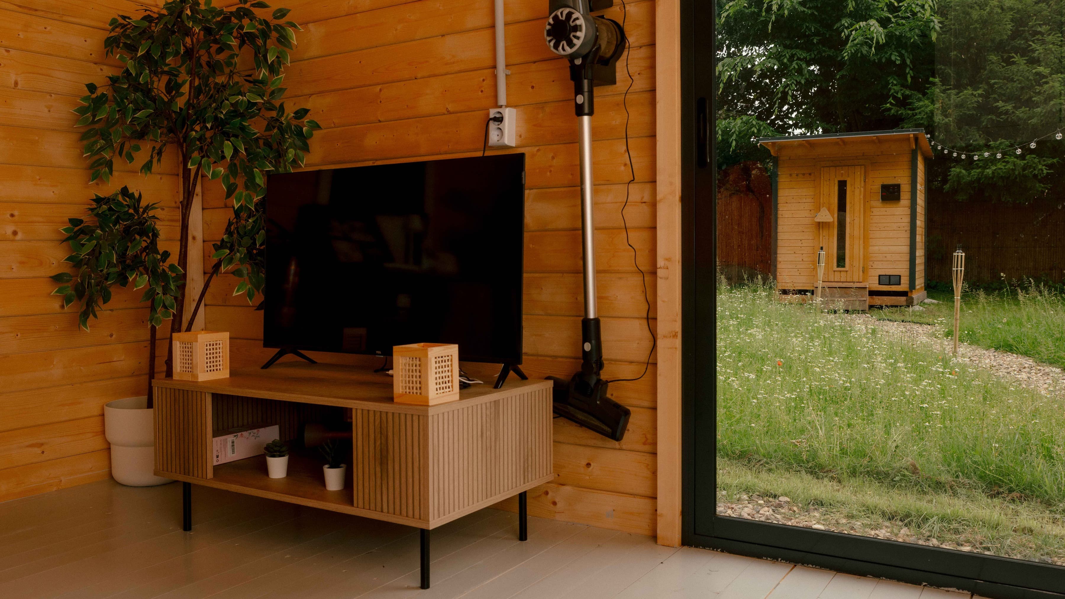 Wohnzimmer in der Cottage vom Bubble Hotel mit Fernseher und Blick auf die private Sauna im Garten.